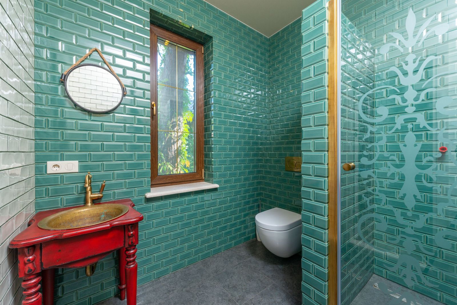 Bathroom with glossy green metro tiles and a brass sink