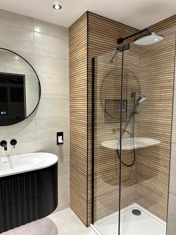 Finished bathroom with wood-slat shower wall, black fittings and a round mirror