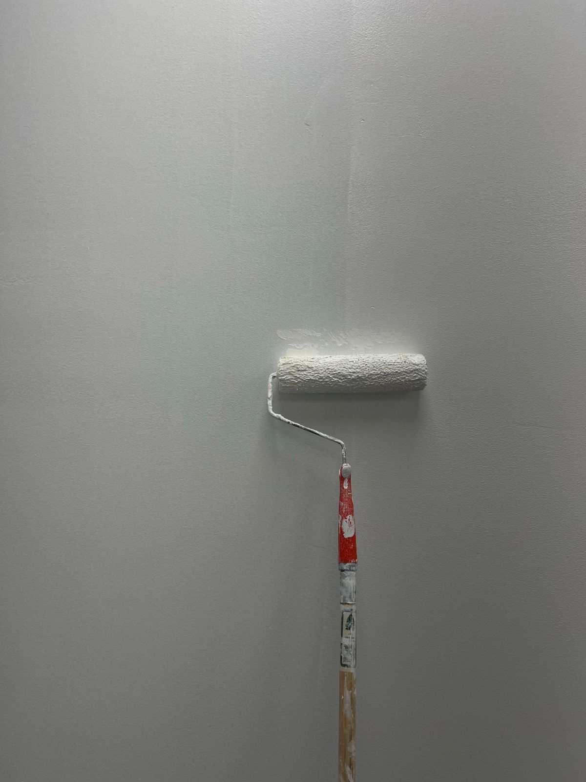 Painter rolling white paint onto a wall