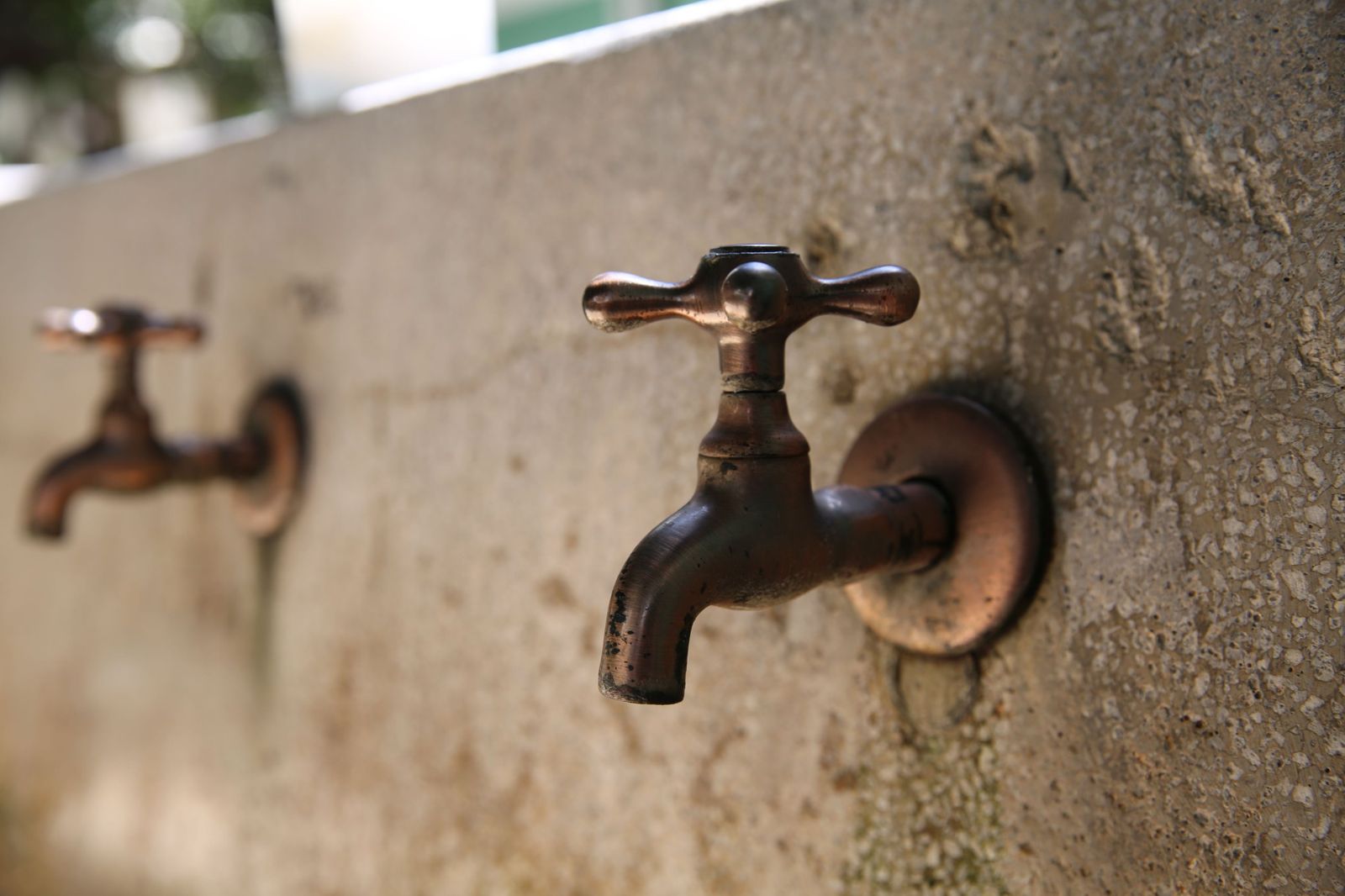 Old copper outdoor taps on a stone wall