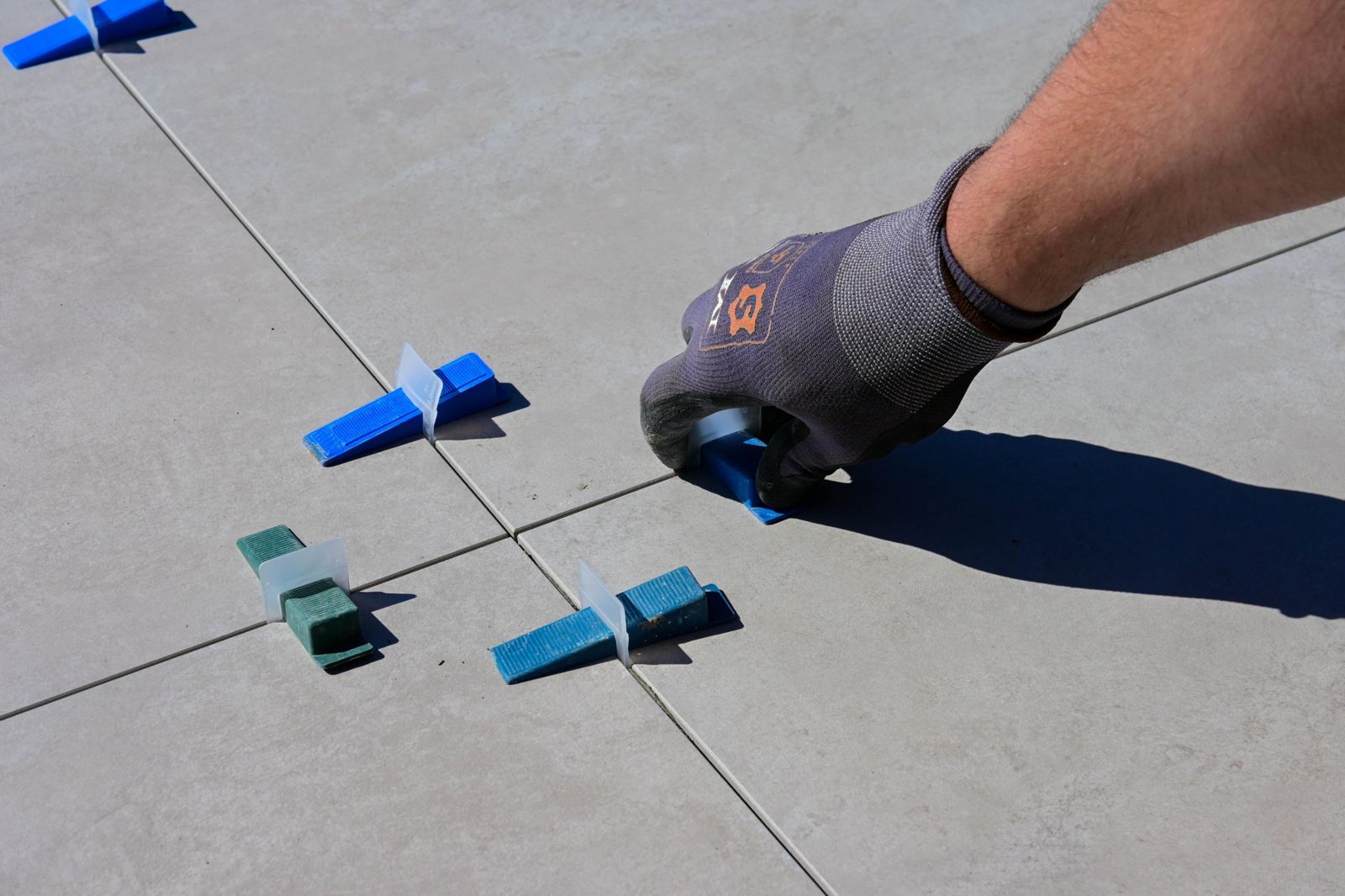 Tiler setting floor tiles with levelling spacers
